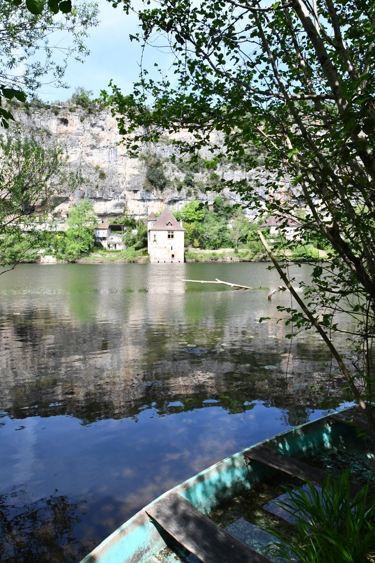Small wooden boat looking across the river to a square stone building with red tiled roof, it's beautiful